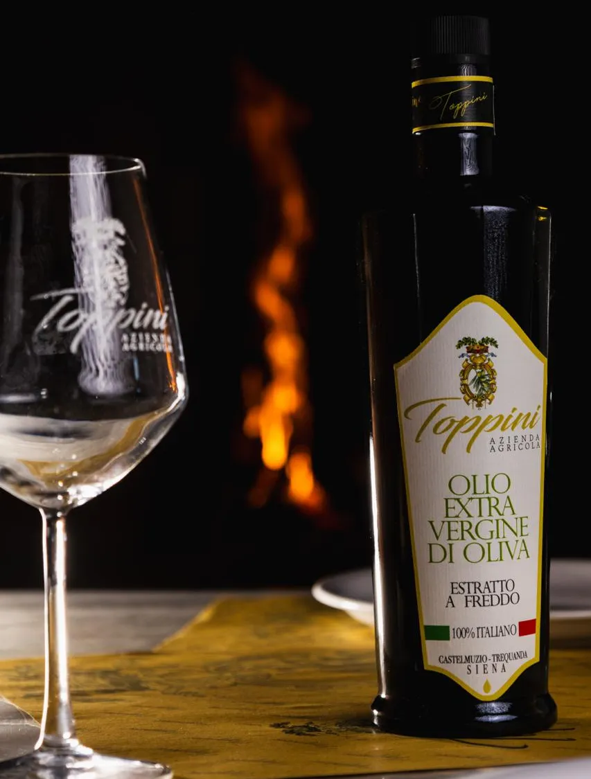 La bottiglia di olio Toppini davanti al fuoco del camino
